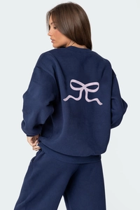 Détail du dos d'un sweat bleu marine avec grand imprimé nœud rose et tissu coton épais