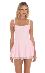 Détail d'une mini robe rose avec bretelles à nœuds et ourlet en tulle plissé blanc