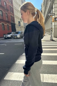 Side view of navy blue zip-up hoodie and grey sweatpants on a city street background