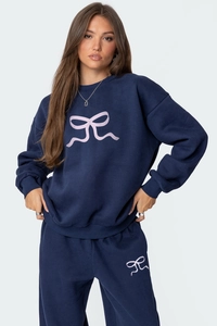 Détail d'un ensemble de sweat bleu marine avec motif nœud rose et pantalon large fluide