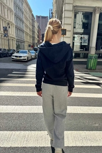 Outdoor street view of navy zip hooded sweatshirt and grey straight-leg sweatpants