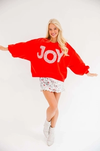 Felpa rossa oversize con scritta JOY abbinata a una gonna di paillettes argento