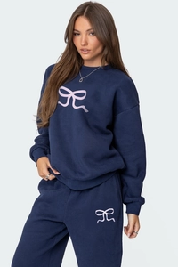 Détail d'un ensemble sweat et jogging bleu marine avec imprimés nœuds roses sur tissu