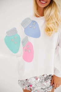 Detail showing white Christmas sweatshirt with sequin star appliques and bulb embroidery