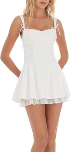 Détail de la robe mini blanche à fines bretelles avec nœuds et ourlet à volants