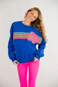 Detail of Merry & Bright sequin lettering and rainbow stripes on blue sweatshirt
