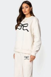 Détail de l'ensemble sweat et pantalon crème avec motif nœud noir et bords-côtes