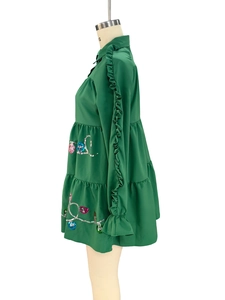 Detailed view of green tiered dress featuring ruffled sleeves and colorful sequin embroidery