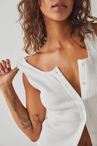 Detailed close-up of white ribbed knit vest featuring delicate lace trim and button closure