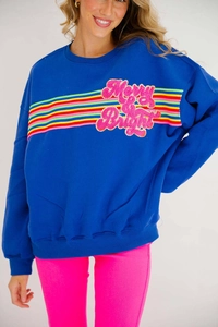 Detail of blue sweatshirt featuring Merry & Bright pink sequin embroidery and rainbow stripes