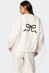 Détail d'un sweat-shirt crème avec un grand graphique de nœud noir imprimé dans le dos