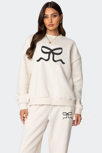 Détail d'un ensemble sweat crème avec motifs de nœuds noirs sur un tissu de coton doux