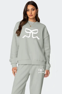 Détail du motif nœud blanc sur le sweat-shirt gris clair et le pantalon de jogging