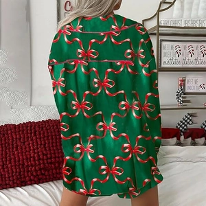 Detail of green satin Christmas pajama top featuring festive red bow prints and pink piping
