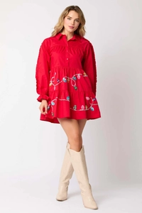 Detail of red tiered Christmas dress featuring colorful holiday bulb patterns and ruffles