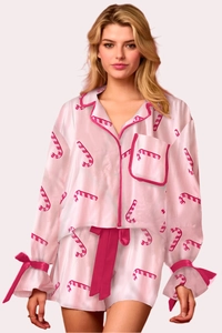 Dettaglio del pigiama in raso rosa con stampe di bastoncini di zucchero e fiocchi rossi