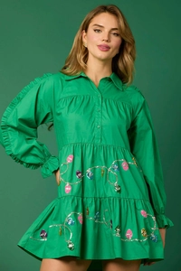 Detail of green Christmas dress showing sequin light string patterns and layered ruffles