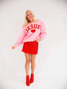 Pink crewneck sweatshirt with heart and JESUS embroidery paired with red sequin skirt