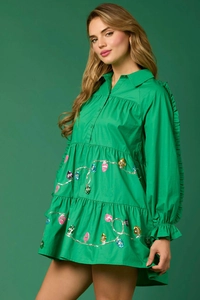 Detail of vibrant green tiered dress with festive colorful bulb sequin patterns