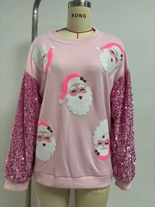 Detail of pink Christmas sweatshirt with sequin Santa patterns and sparkling sleeves