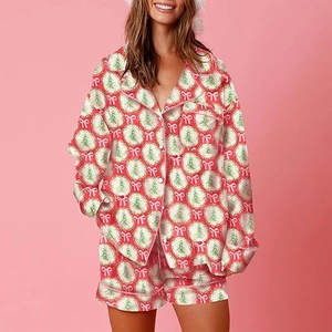 Close-up of pink satin Christmas pajama set with festive tree and bow patterns