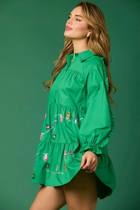 Detailed close-up of festive green tiered dress with sequined Christmas light patterns