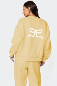 Détail du motif de nœud blanc au dos du sweat à col rond jaune crème épais