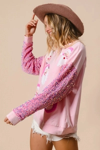Detail of pink Christmas sweatshirt featuring sequin sleeves and Santa Claus plush embroidery