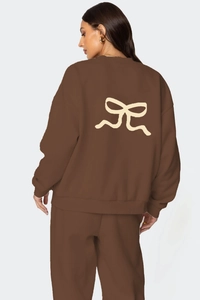 Détail d'un ensemble de détente marron ample avec imprimé nœud beige au dos du sweat