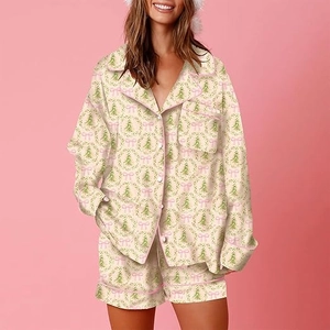 Close-up of Christmas pajama set featuring festive bow and tree prints with pink piping