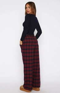 Detail of red plaid wide-leg pants and black slim fit long-sleeve top on model