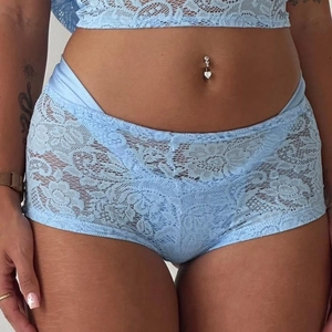 Detail of light blue floral lace boxer shorts with silky trim on a model waist