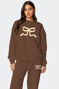 Détail de l'ensemble de détente marron café avec motif nœud beige sur le sweat et le pantalon