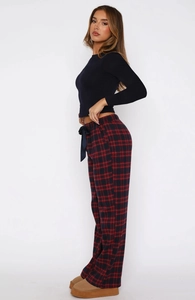 Detail of red and black plaid trousers with a black ribbon bow at the elastic waist