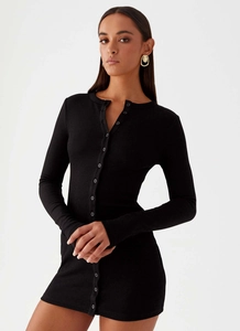 Close-up of the ribbed knitting texture and button detailing on a slim-fit black dress