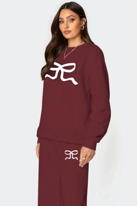 Détails d'un survêtement rouge foncé avec motif nœud blanc sur le sweat et pantalon