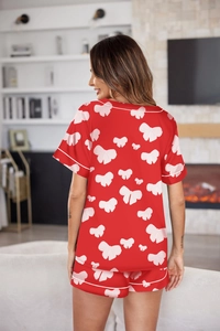 Vista trasera del pijama de satén rojo con estampado de lazos blancos en un modelo