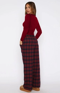 Detail of red slim top and red-black plaid wide-leg pants on model with side pockets