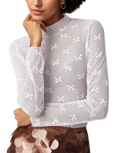 Detail of white mesh lace top featuring bow embroidery and polka dot patterns