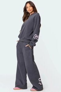 Détail du survêtement gris foncé avec imprimé nœud rose sur la manche et le pantalon