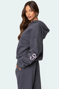 Détail de l'ensemble sweat à capuche gris foncé avec logo rose et pantalon de sport