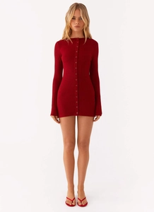 Detail view of deep red knitted long sleeve dress showing fine ribbed texture and buttons
