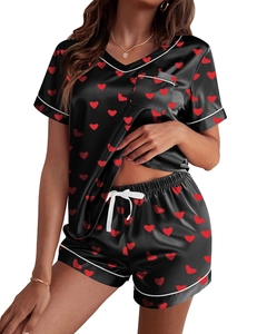 Detalle de pijama de satén con estampado de corazones rojos, cuello en V y vivos blancos