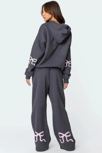 Détail d'un survêtement gris avec nœuds roses sur les manches et le pantalon large