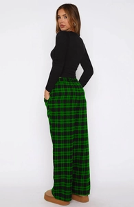 Detail of green and black plaid drawstring trousers and fitted black long sleeve top