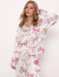 Detail of pink bow patterns on white satin long sleeve pajama set with pink buttons