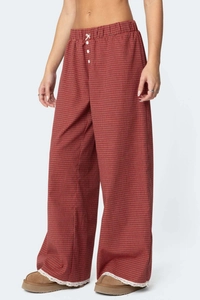 Dettaglio di pantaloni ampi a scacchi rossi con bordo in pizzo e bottoni bianchi decorativi
