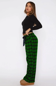 Detail view of women's long sleeve black top and green plaid pants with drawstring bow