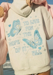 Close-up of butterfly embroidery and vintage lettering on beige hoodie back