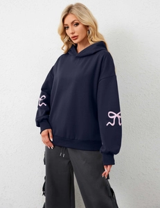 Close-up of navy blue hoodie featuring pink ribbon bow prints on long sleeves